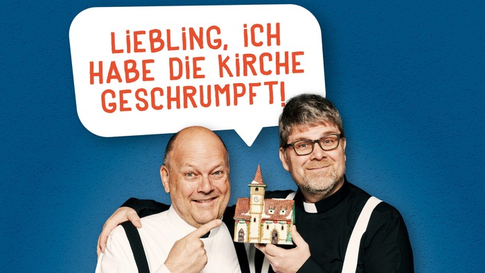 Zwei Männer halten ein Miniaturmodell einer Kirche, einer spricht in einer Sprechblase über die Kirche