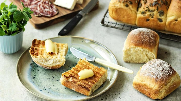 Billede af brød med smør og chokolade, spredt på en hvid tablett.