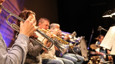 Eine Gruppe von Musikern spielt Blechblasinstrumente auf einer Bühne.