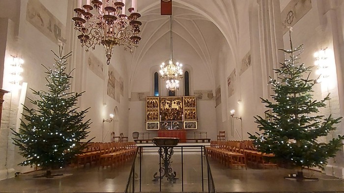 Indre del af kirke med julestænder og lys.