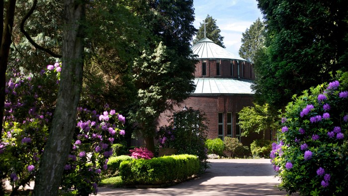 Ein malerischer Gartenweg mit blühenden Büschen und einem charmanten Gebäude im Hintergrund