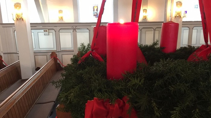Weihnachtsdekoration in Kirche mit grünen Kränzen und roten Schleifen