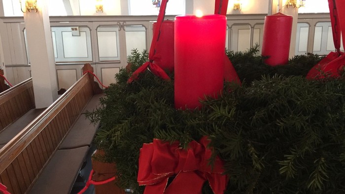 Weihnachtsdekoration in Kirche mit grünen Kränzen und roten Schleifen