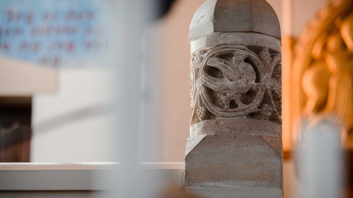 En skulpturert stenkolonne med udvidede detaljer i et rom.