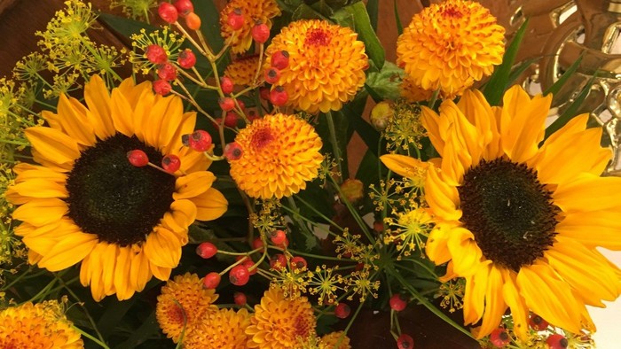 En blomsterstang med store solsikker og andre farvede blomster.