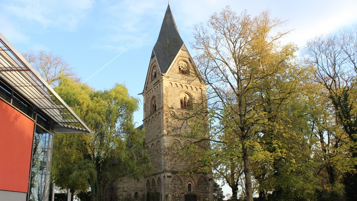Alte Kirche mit hohem Turm und grünem Rasen
