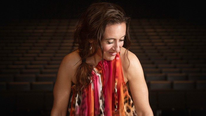 En kvinde i farverig kjole spiller piano.