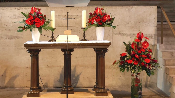 Ein Altar mit roten Blumen und Kerzen in einer Kirche