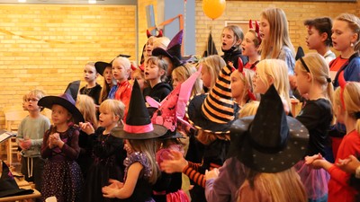 Børn og voksne på Halloween-fest med kostumer og balloner