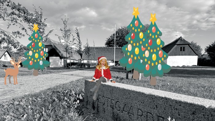 En lille pige i juletrøje sidder på en mur med to store juletræer og en rød elg i baggrunden