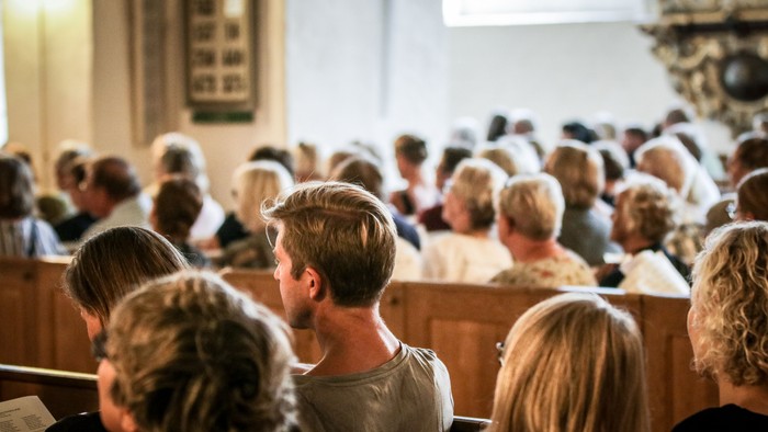 En kirkefuld med mennesker under gudstjeneste.