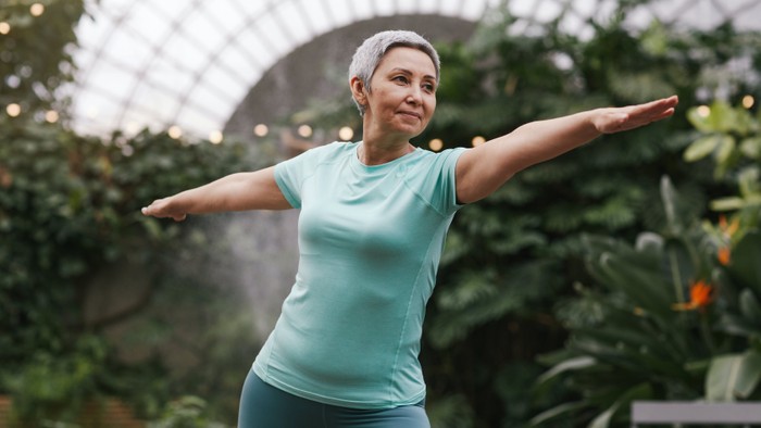 Frau übt Yoga in einem Gewächshaus