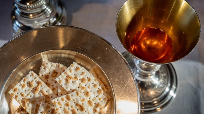 Ein silberner Teller mit Matzen, daneben ein Glas mit Rotwein
