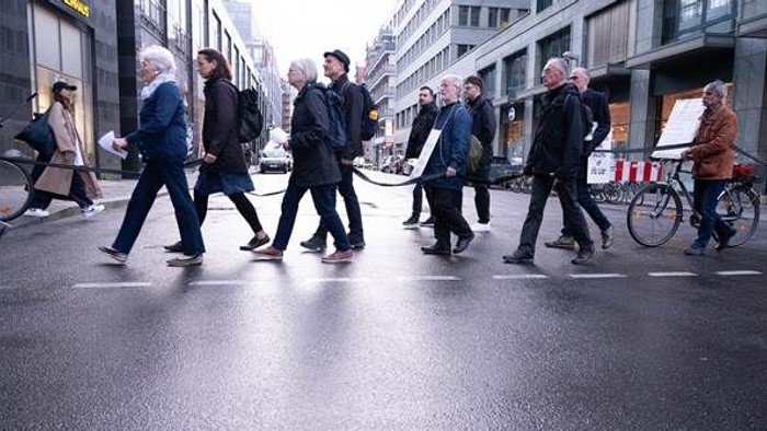Eine Gruppe von Menschen überquert eine nasse Straße in der Stadt.