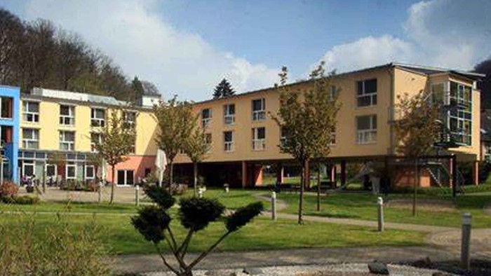 Modernes Wohngebäude mit Grünfläche und Bäumen im Vordergrund