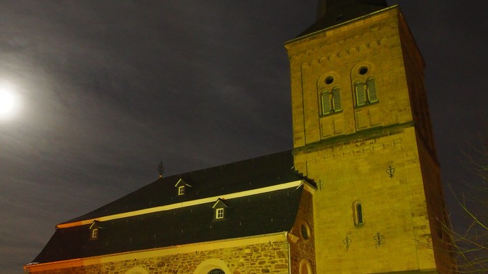 Kirchengrundstück mit beleuchtetem Weihnachtsbaum und Mondschein