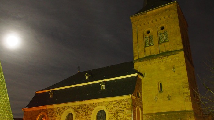 Kirchengrundstück mit beleuchtetem Weihnachtsbaum und Mondschein