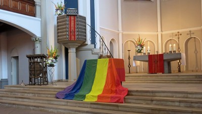 Bunte Flagge liegt auf Kirchenstufen vor Kanzel