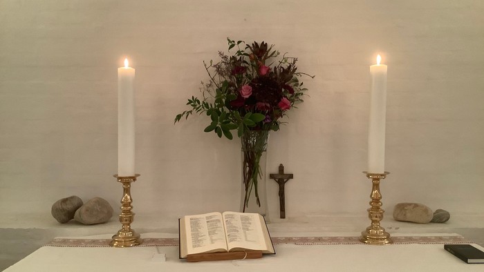 En altertavle med lysede lygter, blomster og bibel