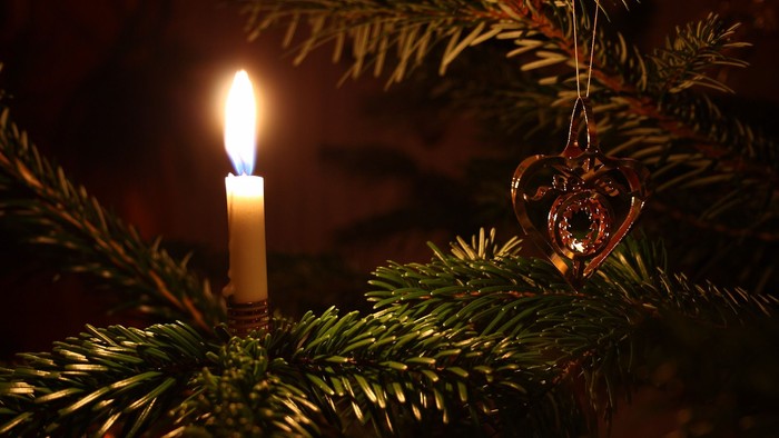 En lysende lyse på en juletræ, med et hjerteformet pynt.