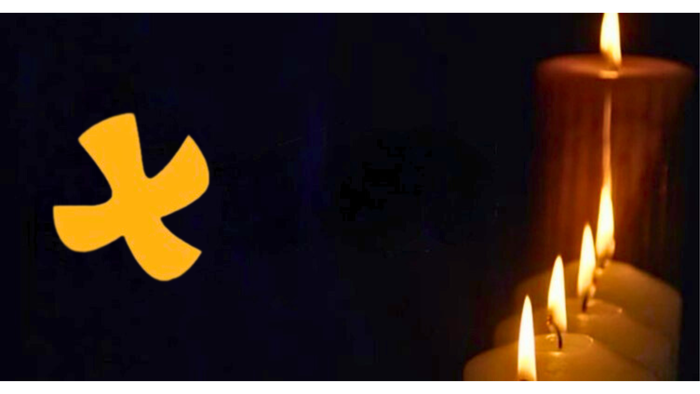 Ein gelbes Symbol und brennende Kerzen vor dunklem Hintergrund