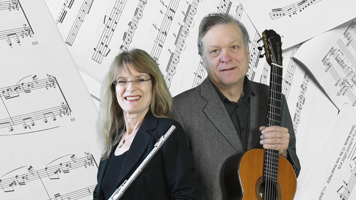 Ein Mann und eine Frau halten Instrumente und stehen vor Notenblättern