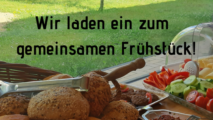 Ein Tisch mit verschiedenen Broten und Gemüsestücken, im Hintergrund ein Baum und ein Gebäude