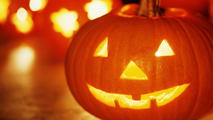 En glødende halloweenlygte i form af en pæpperrodde med en smilende ansigt.