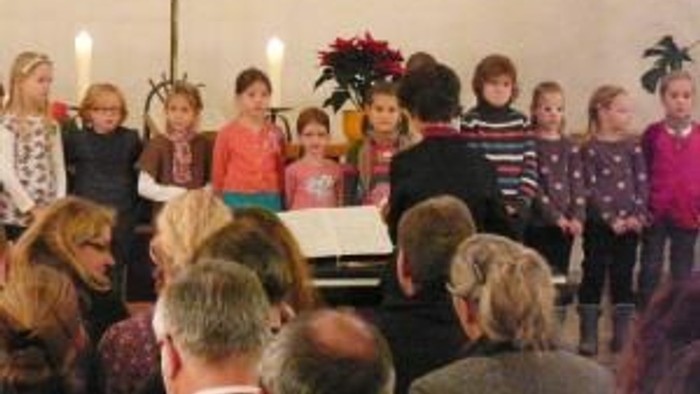 Ein Kinderchor singt vor einem Publikum.