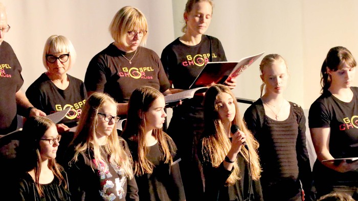 Eine Gruppe von Menschen singt gemeinsam, einige halten Notenblätter