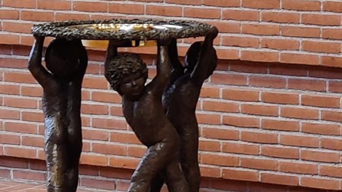 Bronzefigur af to børn, der bærer en plate på et murstenvægge