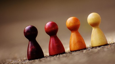 Vier bunte Holzfiguren in Reihe auf einer texturierten Oberfläche