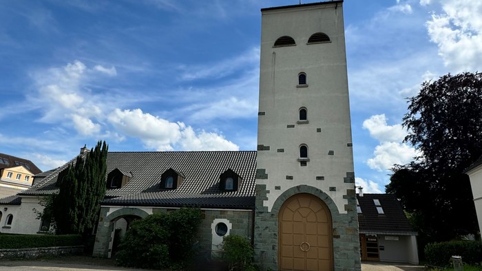 Kirchengebäude mit hohem Turm und Holztür