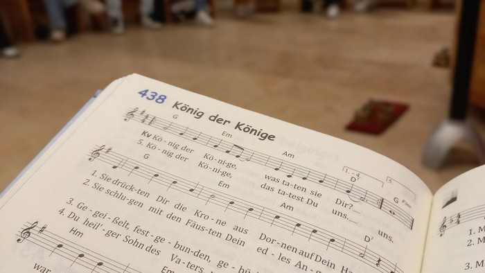 Ein Buch liegt auf dem Boden, Menschen sitzen im Kreis
