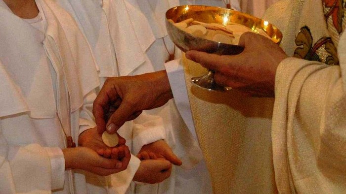 Personen in weißen Gewändern halten eine Schale mit Gegenständen