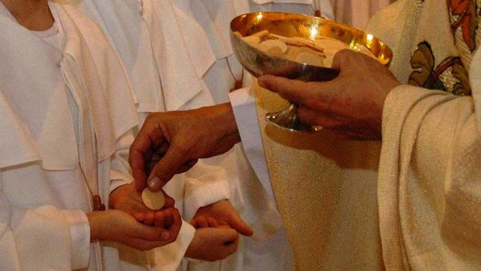 Personen in weißen Gewändern halten eine Schale mit Gegenständen