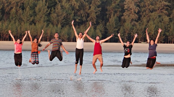 Eine Gruppe von Menschen springt freudig am Strand.