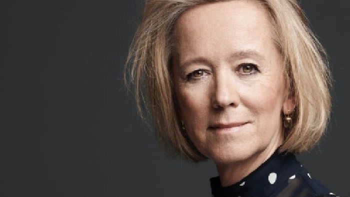 En kvinde med kort, blond hår og en mørk blå jakke.