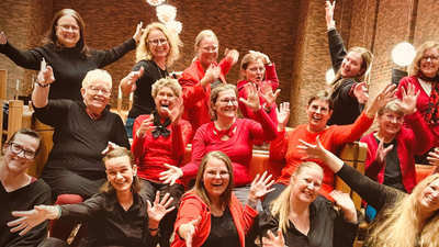 Gruppe af mennesker i rødt og sort tøj, der poser sammen, nogle med fredstegn.