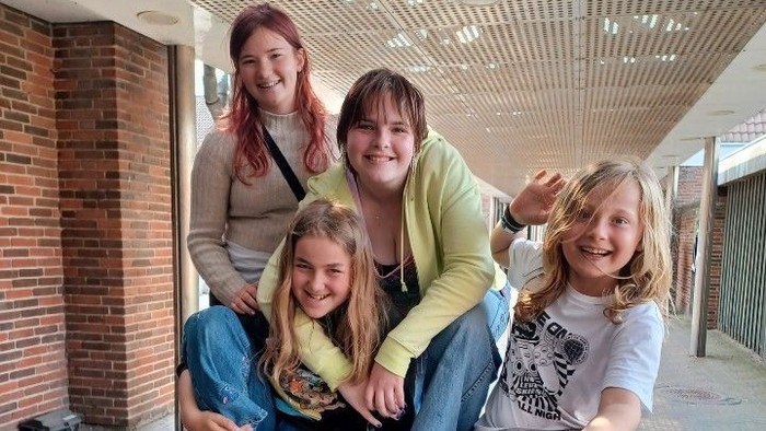 Fire piger sidder på en stor sten under en overbygning