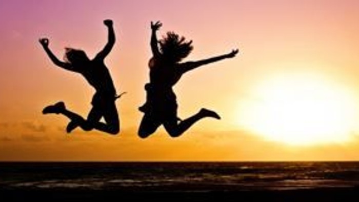 Zwei Personen springen vor Sonnenuntergang in die Luft.