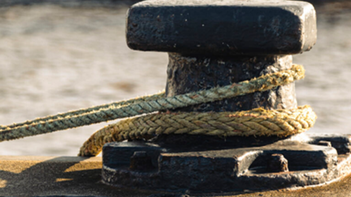Seil an einem Poller auf einem hölzernen Steg festgemacht.