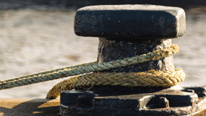 Seil an einem Poller auf einem hölzernen Steg festgemacht.