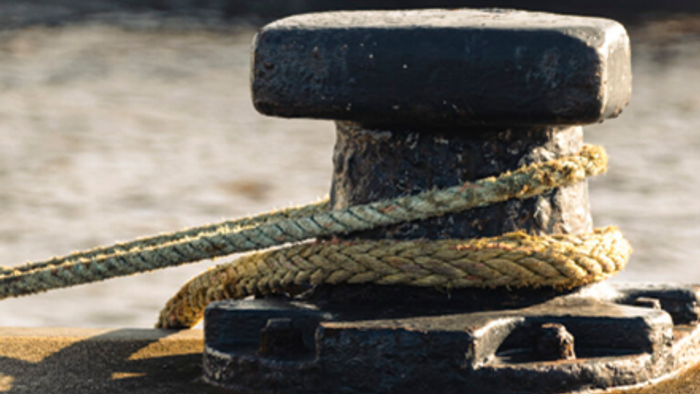 Seil an einem Poller auf einem hölzernen Steg festgemacht.