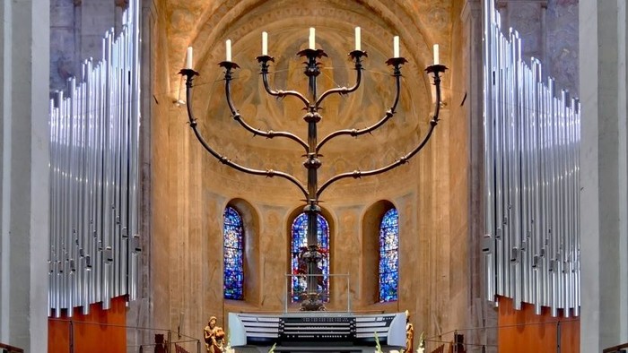 Innenraum einer Kirche mit großem Leuchter und farbenfrohen Fenstern