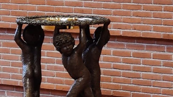 Bronzefigur af to børn, der bærer en plate på et murstenvægge