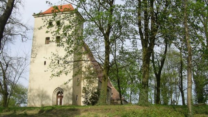Kirche Booßen auf einer Anhöhe umgeben von Bäumen.