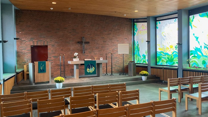 Moderne Kirche mit Holzstühlen und bunten Glasfenstern