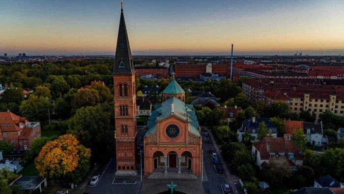 En stor kirke med to tårne i en by ved solnedgang