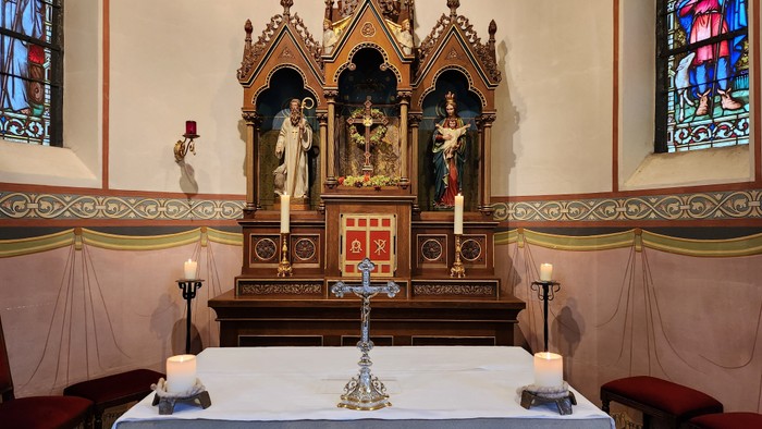 Altar in Kirche mit Kreuz, Kerzen und Heiligenbildern